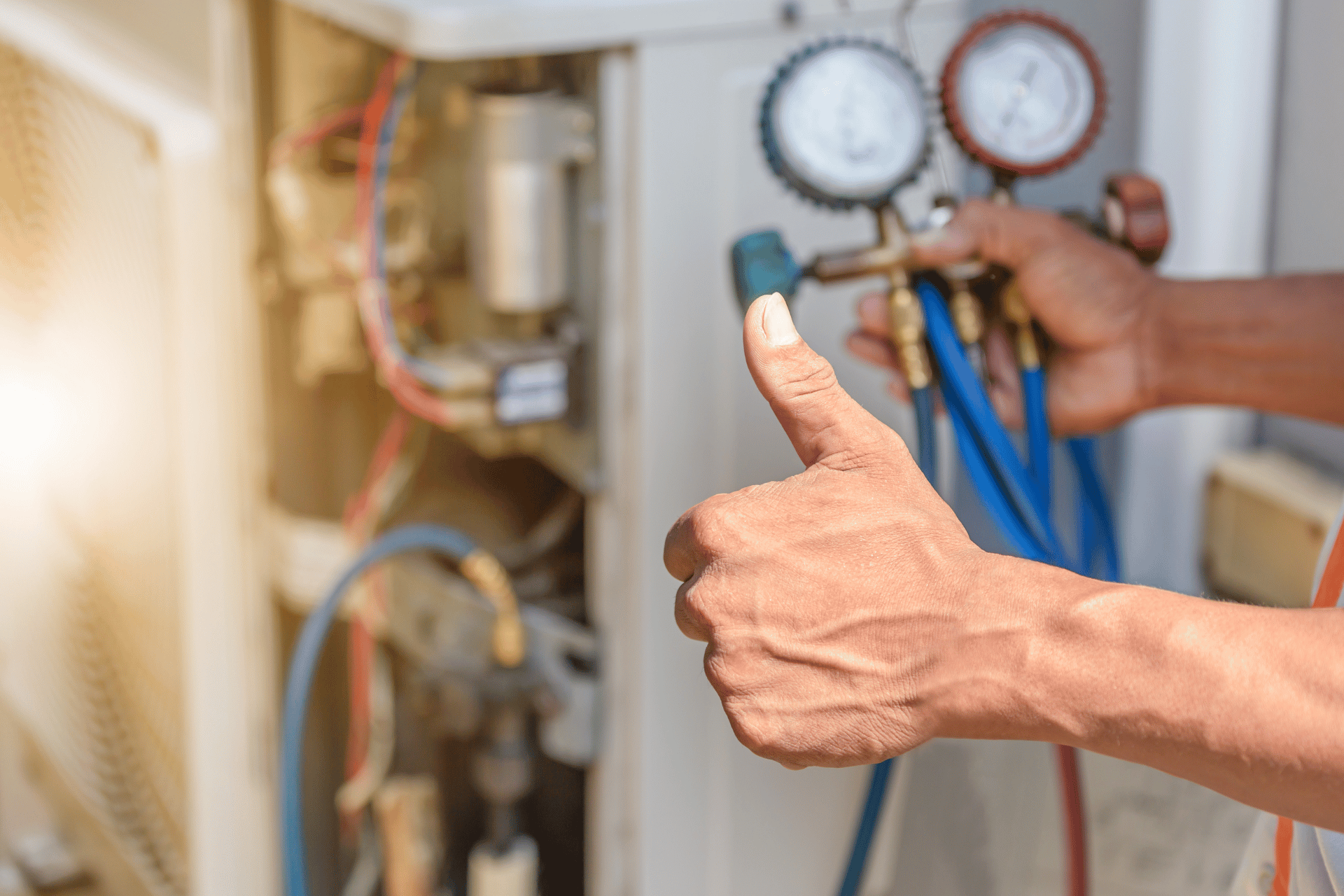 Untitled design - 2024-07-30T203241.194 A person's hand gives a thumbs-up while holding pressure gauges connected to an HVAC unit, indicating approval or successful maintenance. The HVAC system's internal components and colorful wires are visible, with the sunlight shining in the background, reminiscent of a bright day on the Sunshine Coast.
