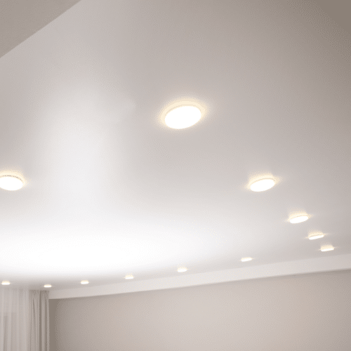 Untitled design (3) A modern ceiling with multiple small, round recessed lights. The lights are uniformly distributed, providing a soft, even illumination reminiscent of the Sunshine Coast. White walls complete the minimalist design, and sheer curtains are visible in the corner.